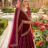 Bride in rosewood maroon bridal lehenga with dupatta draped over head, standing in a rose garden
