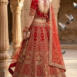 Crimson bridal lehenga back view showing embroidered blouse and dupatta drape.
