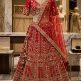 Crimson red bridal lehenga with gold embroidery, front view on display.