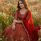 Bride seated in scarlet red bridal lehenga surrounded by wildflowers