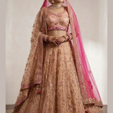 Bride in peach embroidered bridal lehenga with pink dupatta draped over head