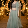 Woman in dusty mint embellished lehenga, fairy-light arch backdrop