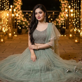 Woman seated in dusty mint lehenga surrounded by candles and petals