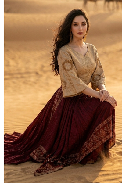 Woman seated in wine and beige fusion skirt set on desert sand