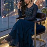 Woman seated in midnight blue embroidered skirt set, city view at night