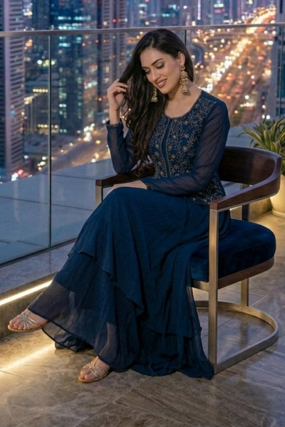 Woman seated in midnight blue embroidered skirt set, city view at night