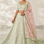 Woman in mint green lehenga with blush pink dupatta, white backdrop