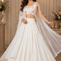 Model in white flowy lehenga with sheer dupatta, front view