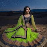 Model sitting wearing Neon lime and navy lehenga showing embroidered border