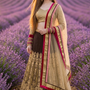 Woman in mocha and gold embroidered lehenga, standing in a lavender field