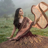 Model sitting in misty outdoor in Royal Wine Embroidered Lehenga displaying flared silhouette