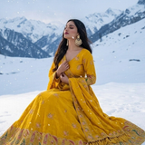 Woman seated in Sunshine Royale mustard embroidered lehenga set in a snowy setting