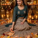 Woman in teal Indo-Western kurta set seated among marigolds and diyas