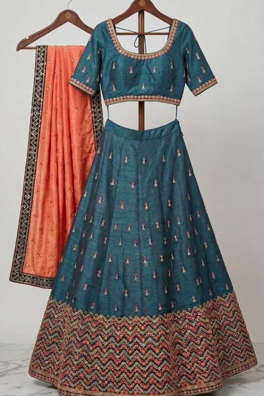 Close-up of teal lehenga blouse with rust orange dupatta detailing 