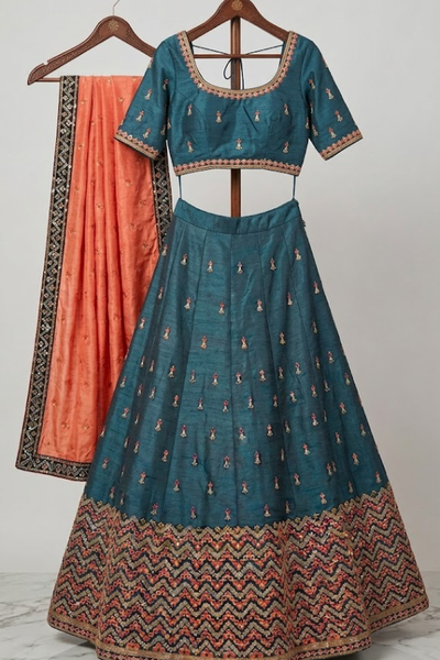 Close-up of teal lehenga blouse with rust orange dupatta detailing 